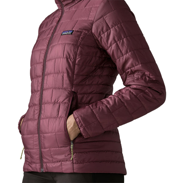 A person wearing the berry fig color Patagonia Women's Nano Puff Hoody showing the side pocket details, on a white background.
