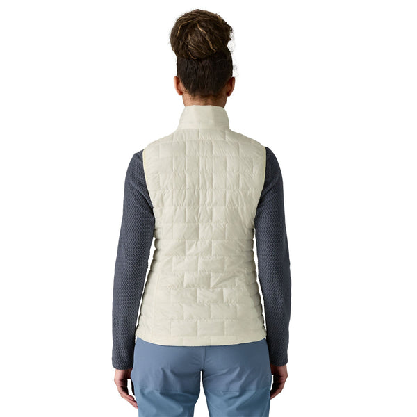 Person wearing the birch white Patagonia Women's Nano Puff Insulated Vest over a black top and blue pants, on a white background.
