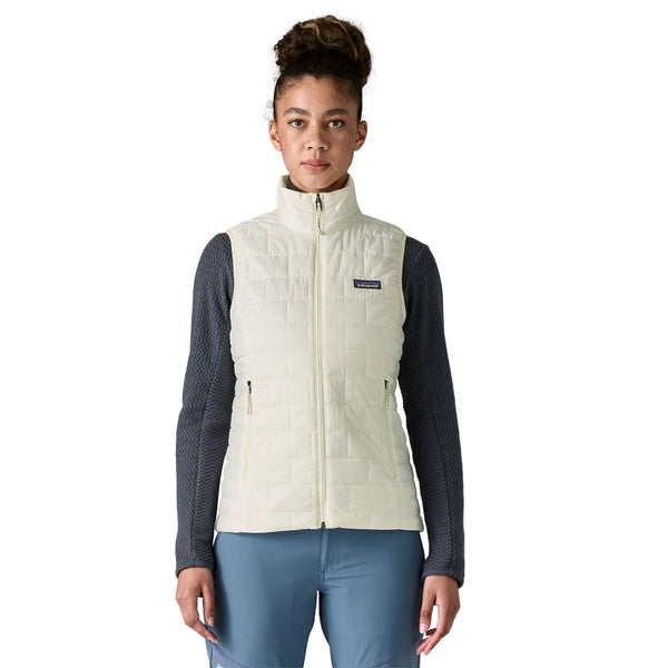 Person wearing the birch white Patagonia Women's Nano Puff Insulated Vest over a black top and blue pants, on a white background.