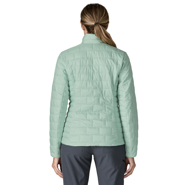 Person wearing grey pants and the thin ice color Patagonia Women's Nano Puff Jacket on a white background.