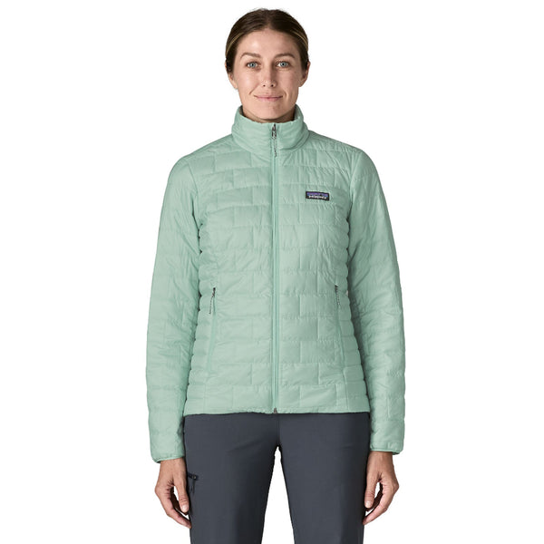 Person wearing grey pants and the thin ice color Patagonia Women's Nano Puff Jacket on a white background.