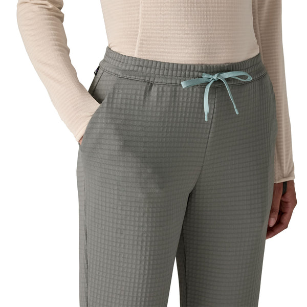 Person wearing a light pink top and noble grey Patagonia Women's R1 Fleece Pants showing the drawstring waist on a white background.