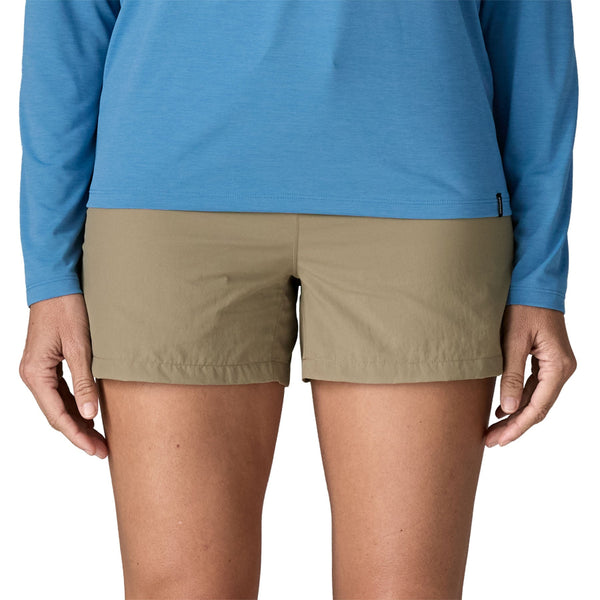 Person wearing a blue top and the Patagonia Women's Sandy Cay Shorts in seabird grey, with drawstring waist and 4 inch inseam, on a white background.