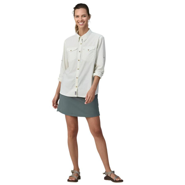 A smiling woman wearing a white shirt and the patagonia women's tech skort in nouveau green showing fit and form, on a white background.