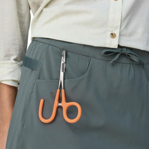 Front view of the patagonia women's tech skort in nouveau green showing pocket and tool loop details with a set of hemostats clipped on.