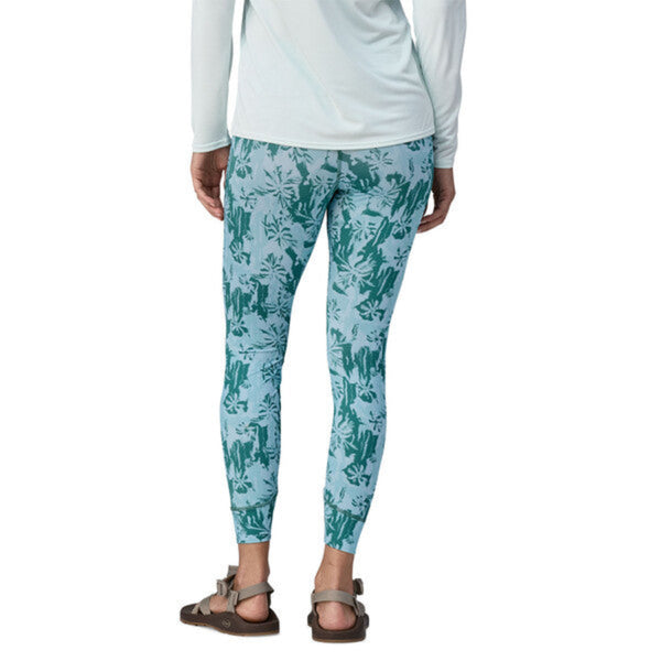 Person wearing Patagonia Women's Topic Comfort UPF Sun Tights in green cliffs and waves pattern on a white background.