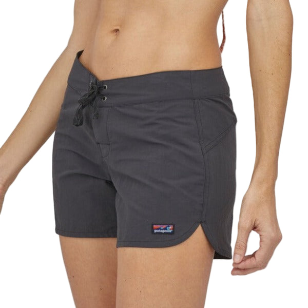 Person wearing black Patagonia Women's Wavefarer Board shorts with a brand logo on a white background.