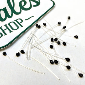 A group of black mono stalk eyes for fly tying on a white background.