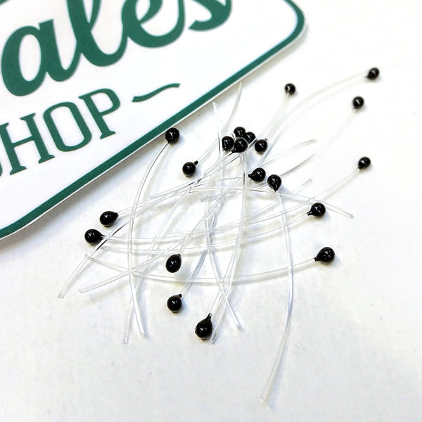 A group of black mono stalk eyes for fly tying on a white background.