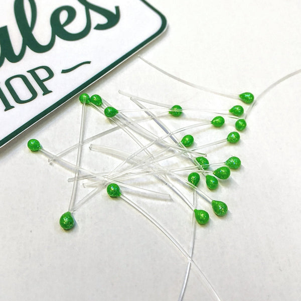 A group of uv sparkle green mono stalk eyes for fly tying on a white background.