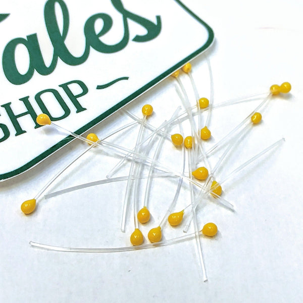A group of yellow mono stalk eyes for fly tying on a white background.