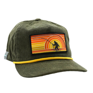 An unstructured 5-panel fit Rep Your Water Sunset Squatch Hat with an olive green corduroy full cloth construction and squatch patch on the front, against a white background.