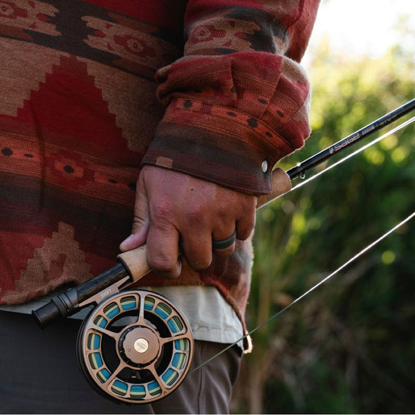 Person holding a Sage Arrow Fly Fishing Rod with a blurred natural background.