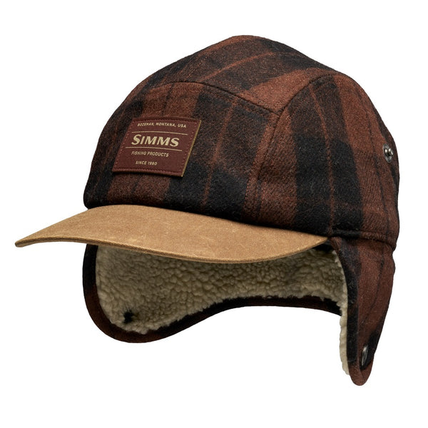 A Simms Coldweather Cap with a brown hickory duke plaid pattern, light brown visor, and cream sherpa ear flaps unfolded down, shown against a white background.