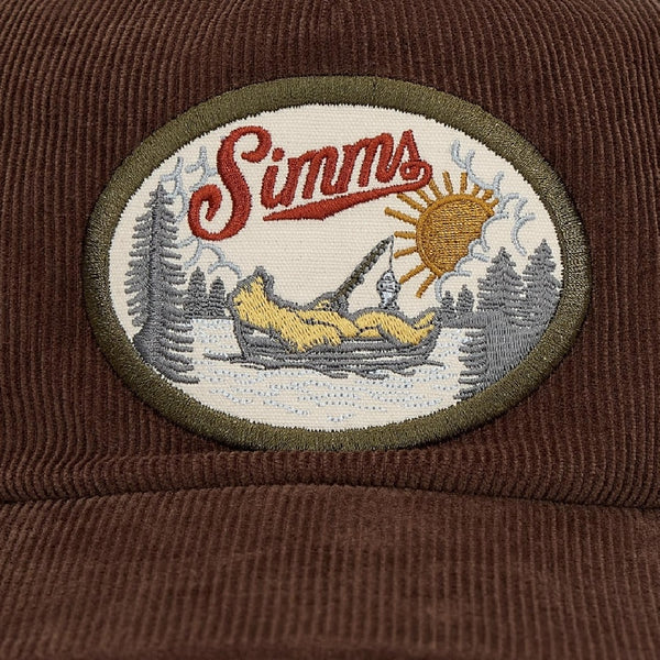 Embroidered patch with 'Simms' logo and nature scene on a brown background.