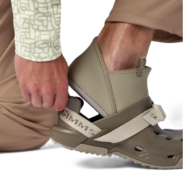 Person putting on an Individual dark stone brown and beige Simms Men's Drifter AT Fishing Shoe showing interior liner on a white background.
