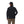 Back view of a person wearing a black Simms Men's Harbor Shacket and cap on a white background.