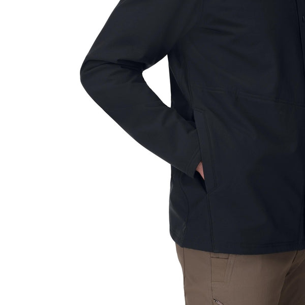 A person wearing a black Simms Men's Harbor Shacket showing the side pocket details on a white background.