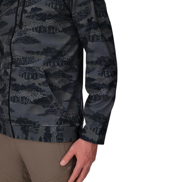 Person wearing a Shroud Black camouflage Simms Men's Rogue Fleece zip front hoody showing a close up of side pocket details on a white background.