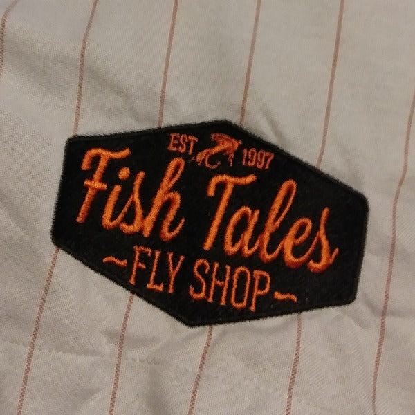 close up of embroidered fish tales logo on simms shop shirt grey with red pinstripes