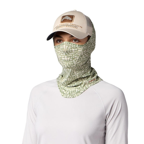 Person wearing a white top and tan hat with the Simms SolarFlex UPF 50+ SunGaiter for covering neck, face and head while fishing, in half moon pale pine print on a white background.