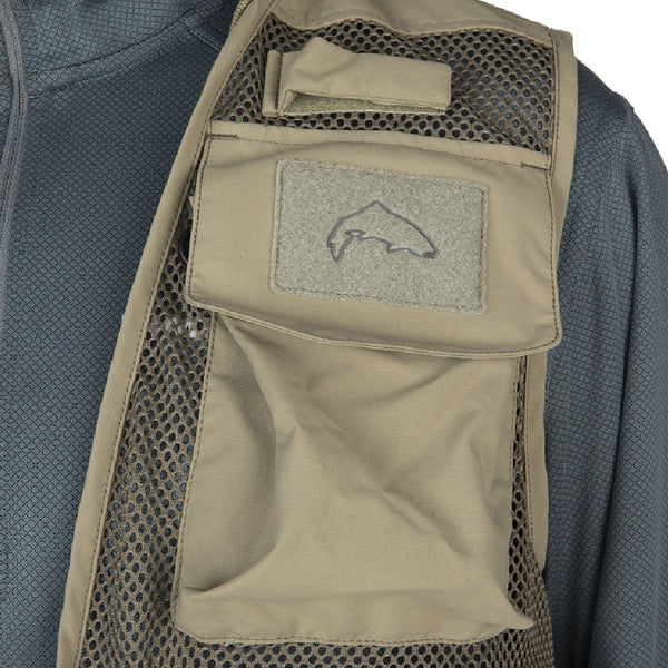Front view of a person wearing the tan Simms Tributary Fishing Vest zoomed in on pocket and mesh details on a white background.
