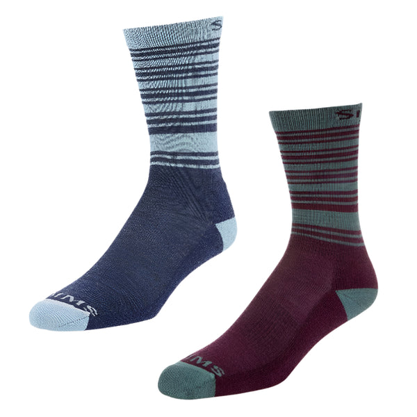 Two pairs of Simms women's merino lightweight hiker socks, one pair in blue and the other in dark red and grey, both with striped patterns and mid-calf height.