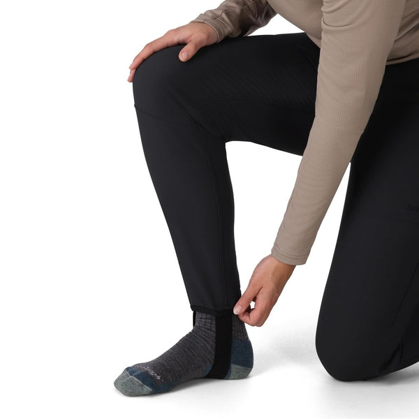Person wearing the black Simms Women's Strata 330 Fleece Bottoms showing cuff detail on a white background.