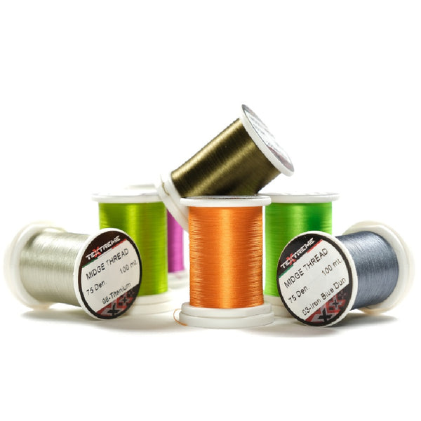 Spools of Textreme Midge fly tying thread in various colors on a white background.