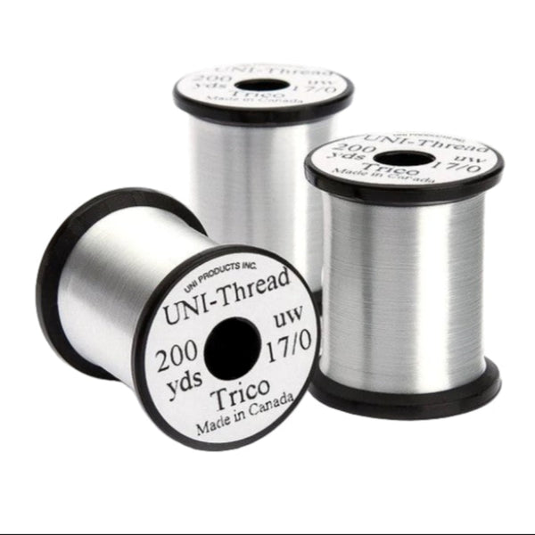A group of 3 spools of white UNI Trico 17/0 fly tying thread n a white background/
