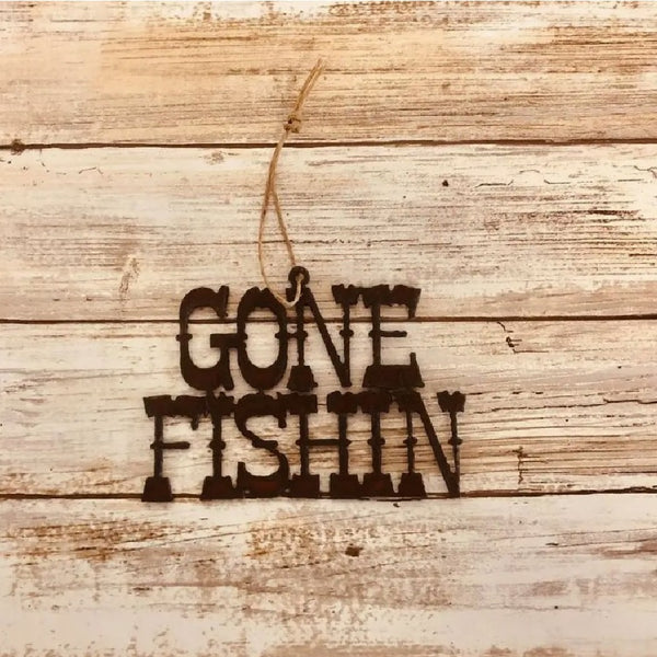 Metallic brown Universal Ironworks Gone Fishin Ornament, on a light wooden background.