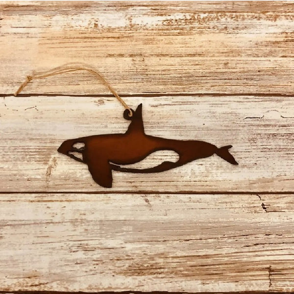 Metallic brown Universal Ironworks Orca Whale Ornament, on a light wooden background.