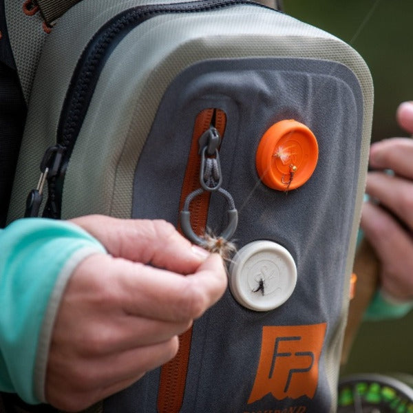 A person setting up a fly fishing line with flies using the Backcountry Labs Solo Magnetic fly holders on a chest pack.