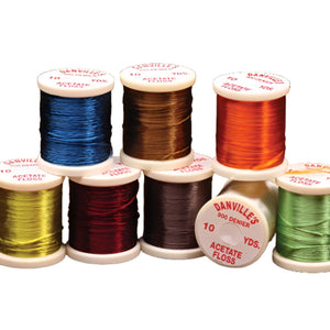 A group of stacked spools of danville acetate floss, in a variety of colors, on a white background.