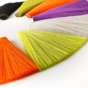 A variety of colored Faux Bucktail fibers used for tying fishing flies, displayed in a fan-like arrangement.