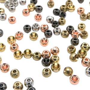 An assortment of fly tying brass beads in gold, copper, nickel and black nickel on a white background.