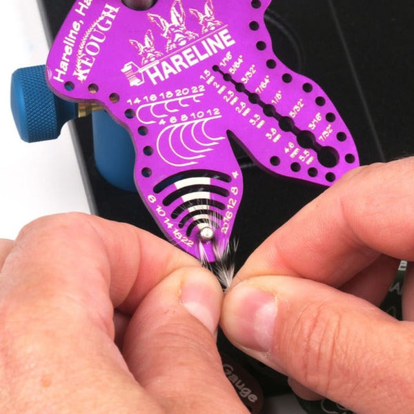hareline hook hackle bead gauge purple color with hands showing how to use hackle measurement