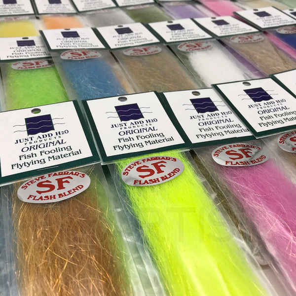 A collection of packaged Just Add H2O Steve Farrar's Flash Blend fly tying material in various colors laid out side by side.