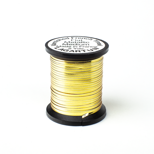 a single spool of gold lagartun varnished flat metal fly tying tinsel on a white background 