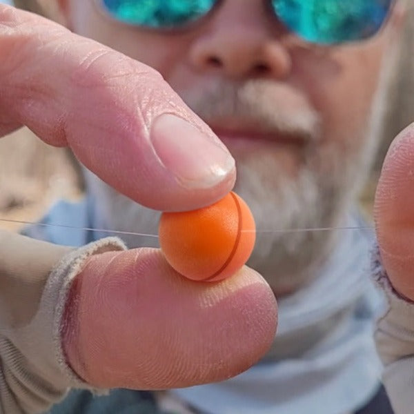 Close up threading an Oros fly fishing indicator on a leader.