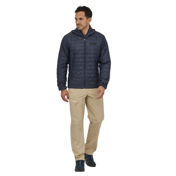 Person wearing the smolder blue Patagonia Men's Fitz Roy Trout Nano Puff Hoody and tan pants on a white background.