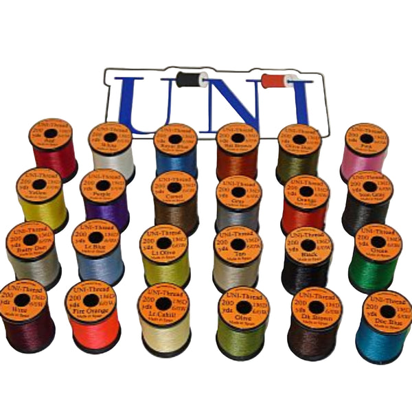 A collection of spools of UNI Standard Fly Tying Thread 6/0 in various colors arranged on a white background.